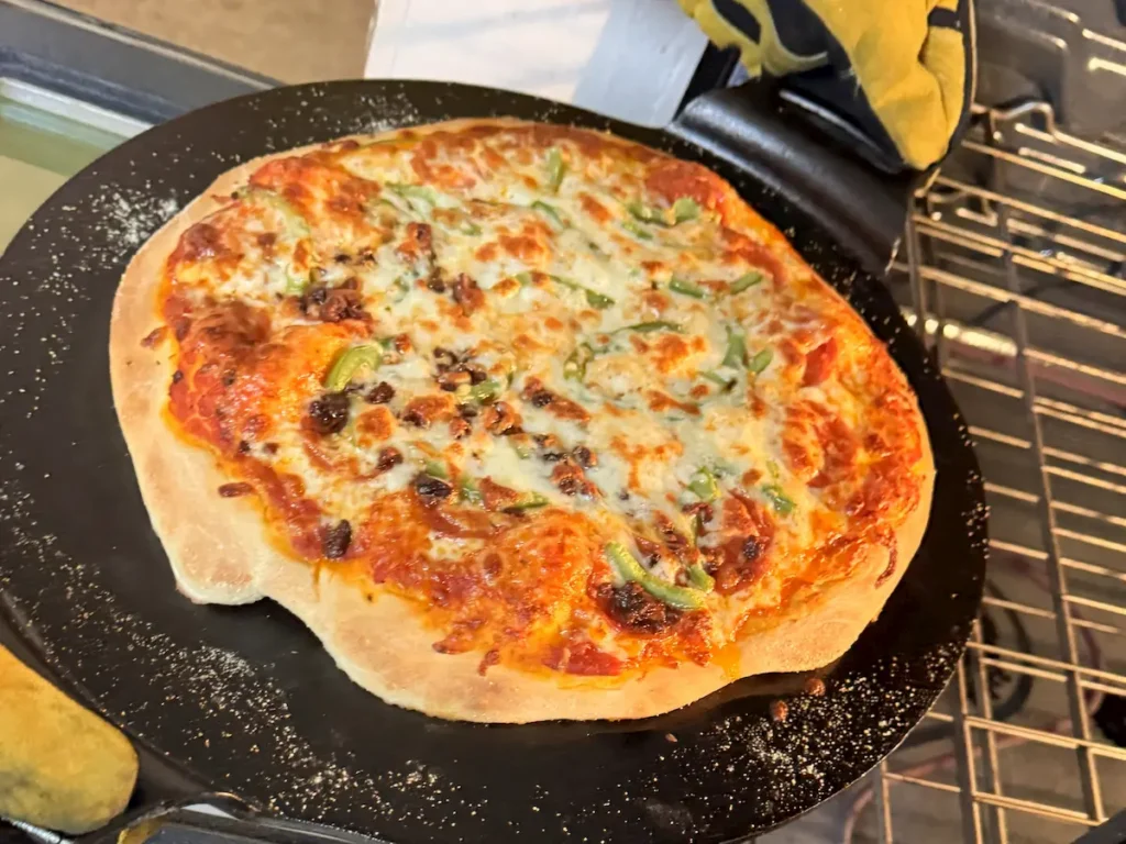 cast iron pizza coming out of an oven