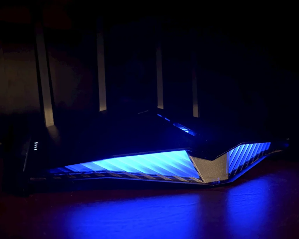 An ASUS RT-AX82U router front Aura RGB light bar glowing blue to act as a live home energy monitor